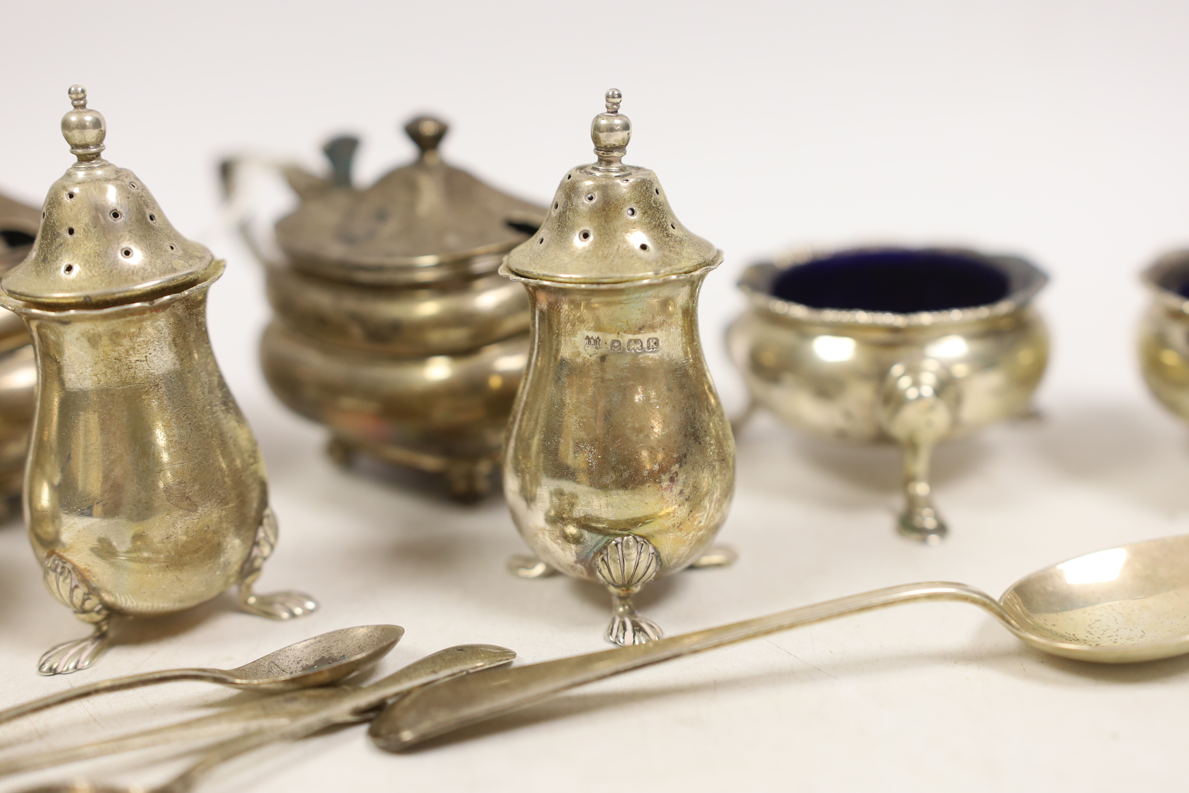 A pair of George V oblong silver lidded mustards with blue glass liners, two other mustards, a pair of peppers, a pair of 'cauldron' salts, three condiment spoons and a teaspoon.